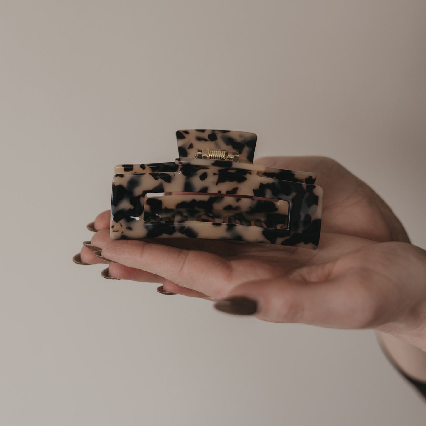 Große eckige Haarspange in Leo-Optik in der Hand präsentiert