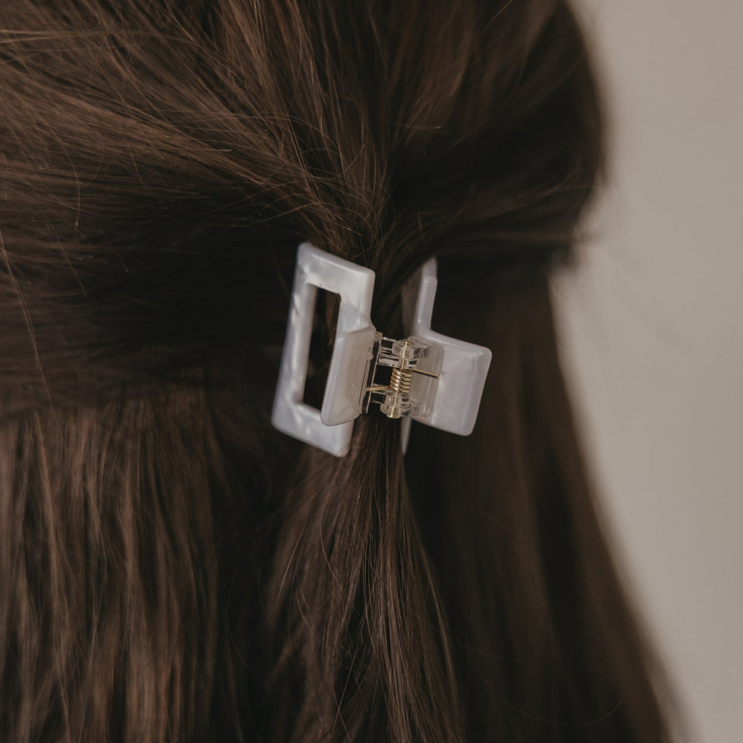 Kleine eckige Haarspange in Perlmutt-Optik im braunen Haar von hinten getragen