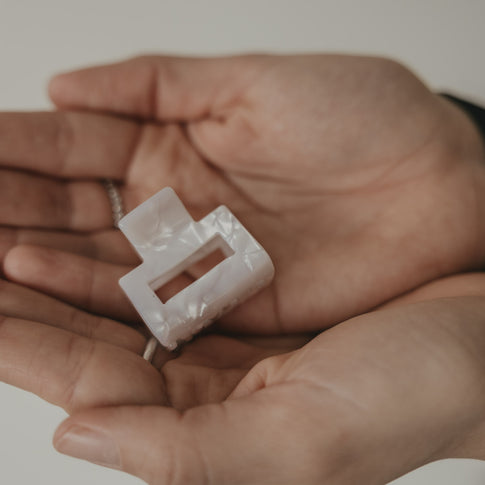 Kleine eckige Haarspange in Perlmutt-Optik in der Hand präsentiert