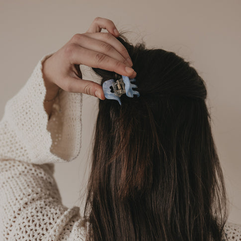 Kleine blaue Haarspange mit Herzdetail wird im Haar befestigt