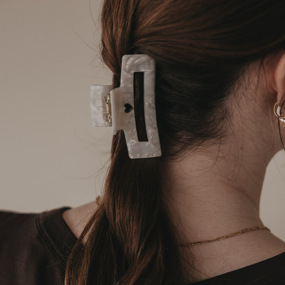 Große eckige Haarspange in Perlmutt-Optik mit schwarzem Herz im Zopf getragen