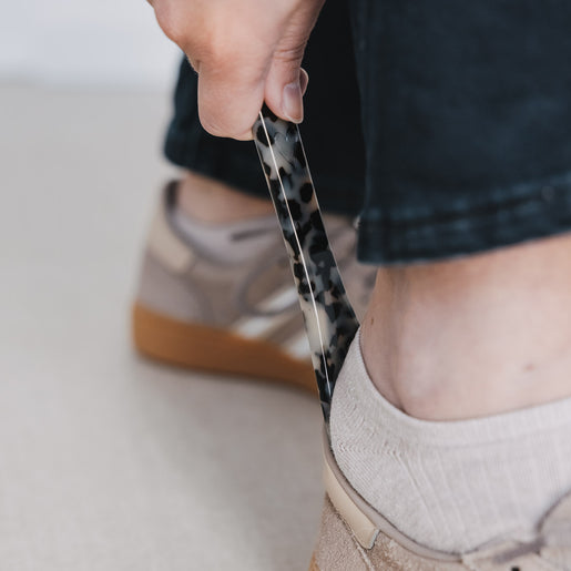 Detailaufnahme Schuhanzieher im Leo-Look beim Anziehen von Schuhen, funktionales und stilvolles Zubehör