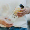 Detail Glasflasche mit Herzmotiv und Zitrone, in der Hand gehalten