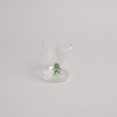 Klares Trinkglas mit grüner Tannenfigur als dekorativem Element im Glasboden