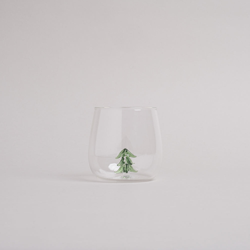Trinkglas mit integrierter grüner Tannenfigur im Glasboden, modernes Design