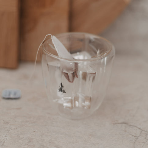 Heißes Getränk mit Teebeutel im doppelwandigen Tannenglas, hitzebeständig und elegant.