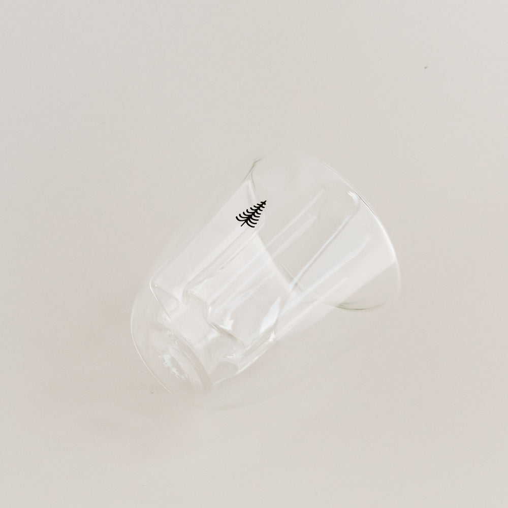 Seitlich liegendes doppelwandiges Tannenglas mit kleinem Baum-Motiv, klare Glasoptik.