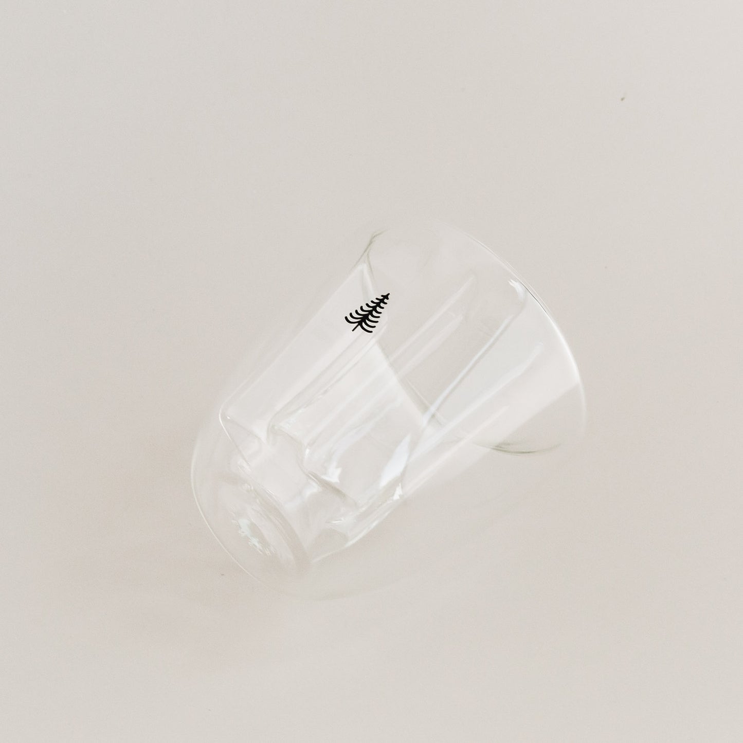 Seitlich liegendes doppelwandiges Tannenglas mit kleinem Baum-Motiv, klare Glasoptik.