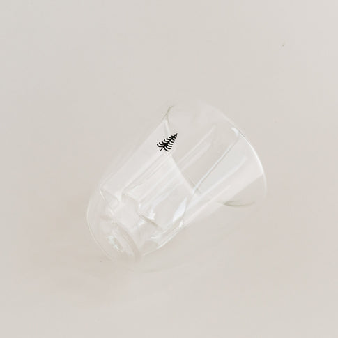 Seitlich liegendes doppelwandiges Tannenglas mit kleinem Baum-Motiv, klare Glasoptik.