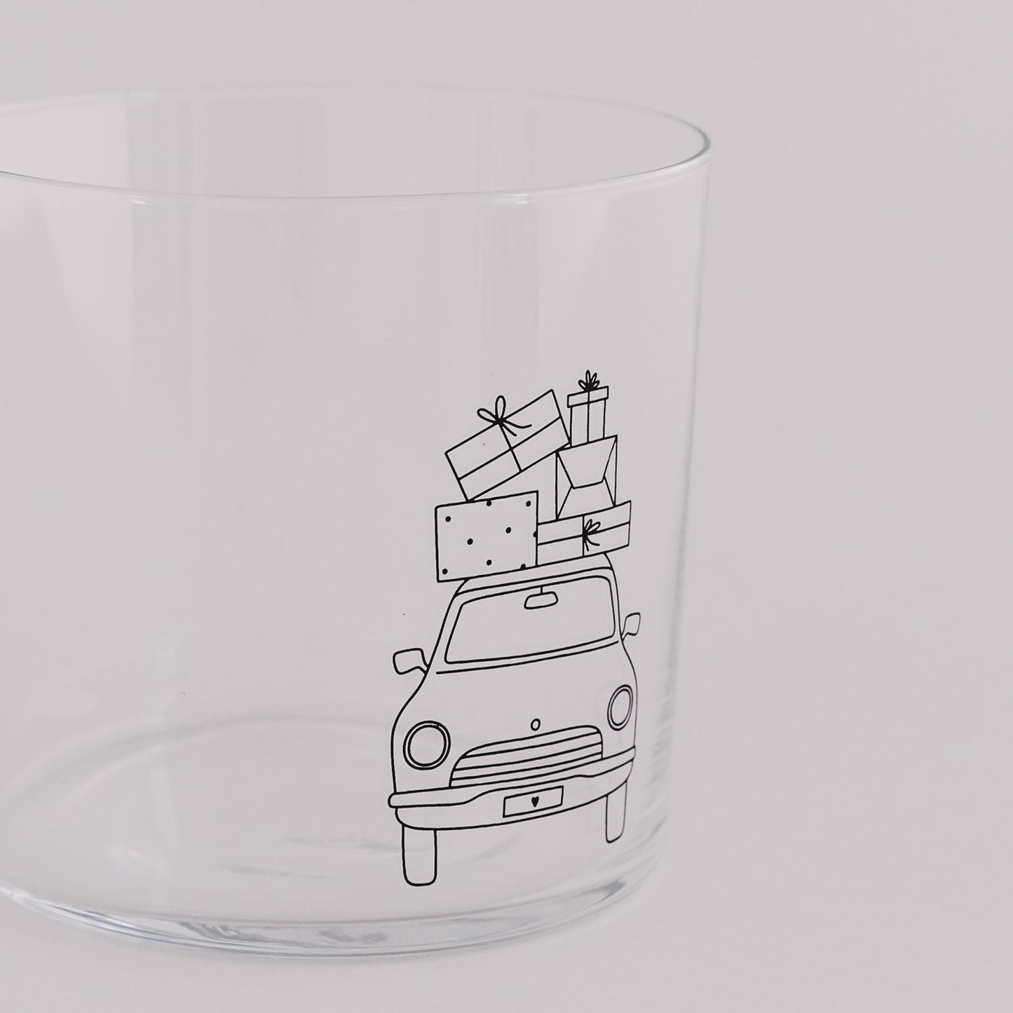 Nahaufnahme des Trinkglases mit Auto und Geschenkstapel – feines Weihnachtsmotiv.