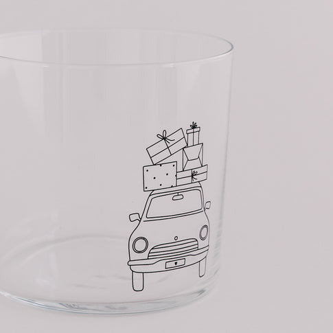 Nahaufnahme des Trinkglases mit Auto und Geschenkstapel – feines Weihnachtsmotiv.