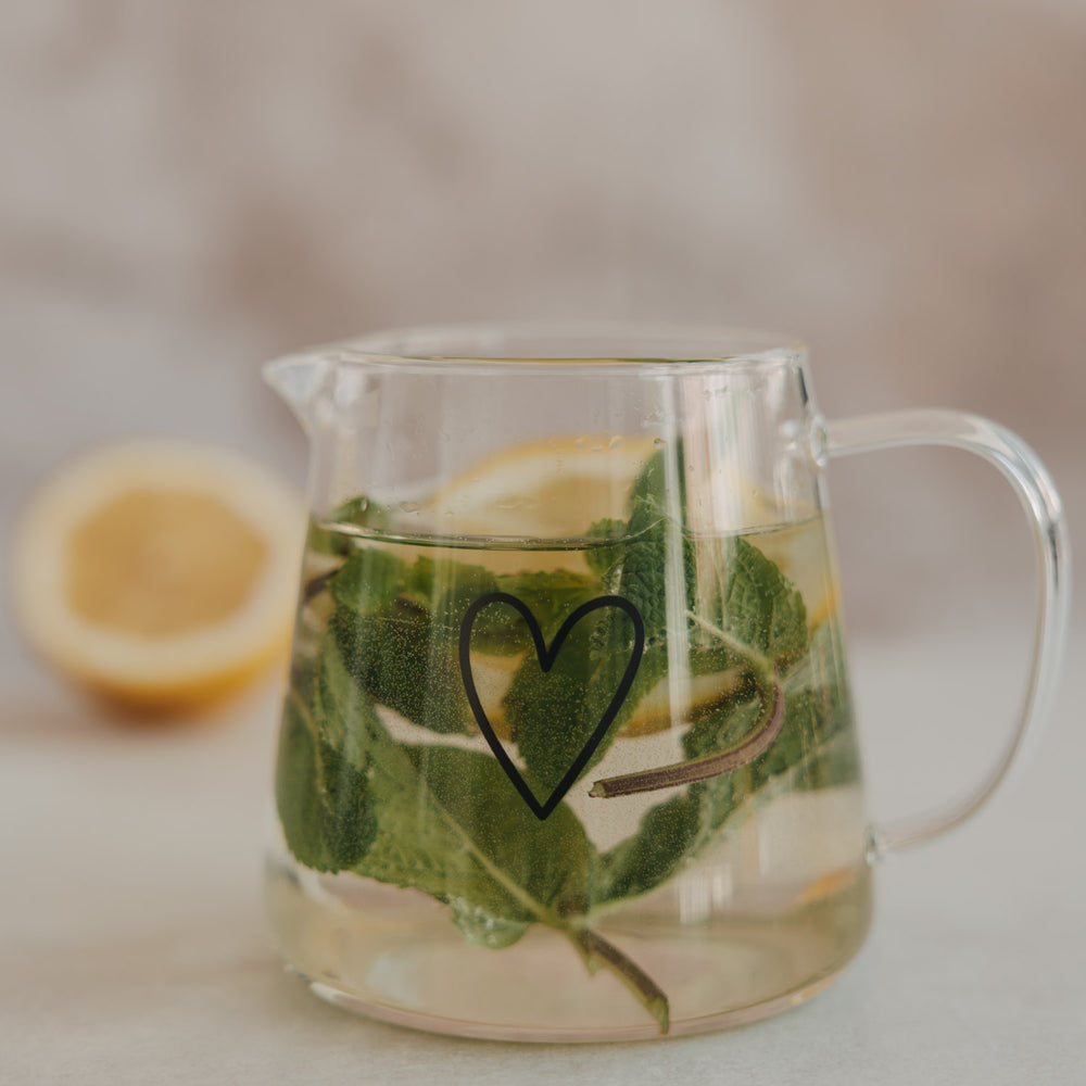 Detail Glas Teekanne mit Herz, Minze und Zitronenscheiben im Wasser für aromatisierte Getränke