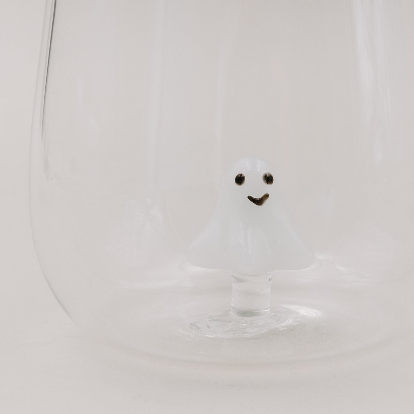 Nahaufnahme des Trinkglases mit schwebender 3D-Geistfigur aus Glas auf hellem Hintergrund