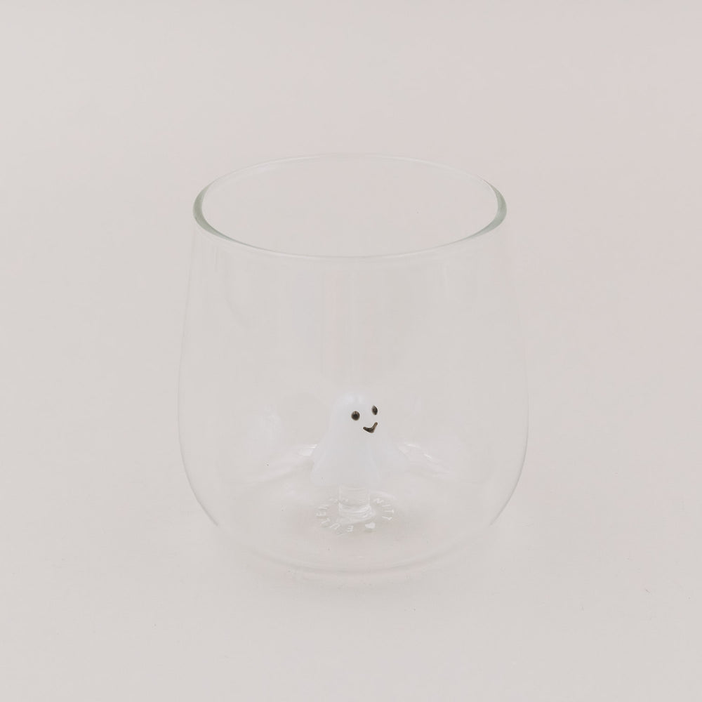 Glas mit kleiner weißer Geistfigur als 3D-Detail am Glasboden, hell und minimalistisch inszeniert