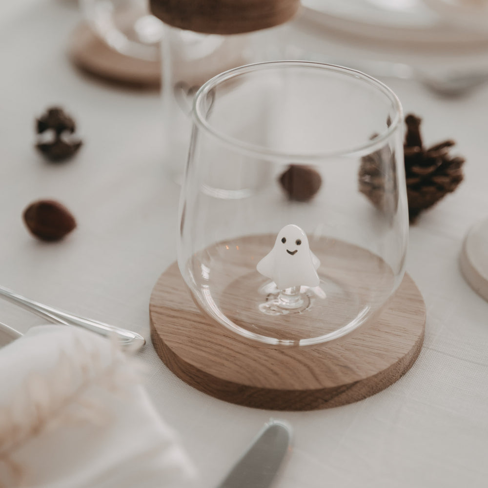 Trinkglas mit schwebender Glasgeistfigur auf weiß gedecktem Tisch mit herbstlicher Deko
