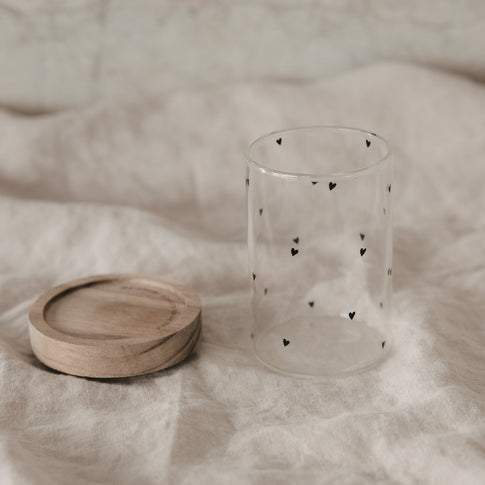 Minivorratsglas mit schwarzen Herzen und abgenommenem Holzdeckel auf Stoff