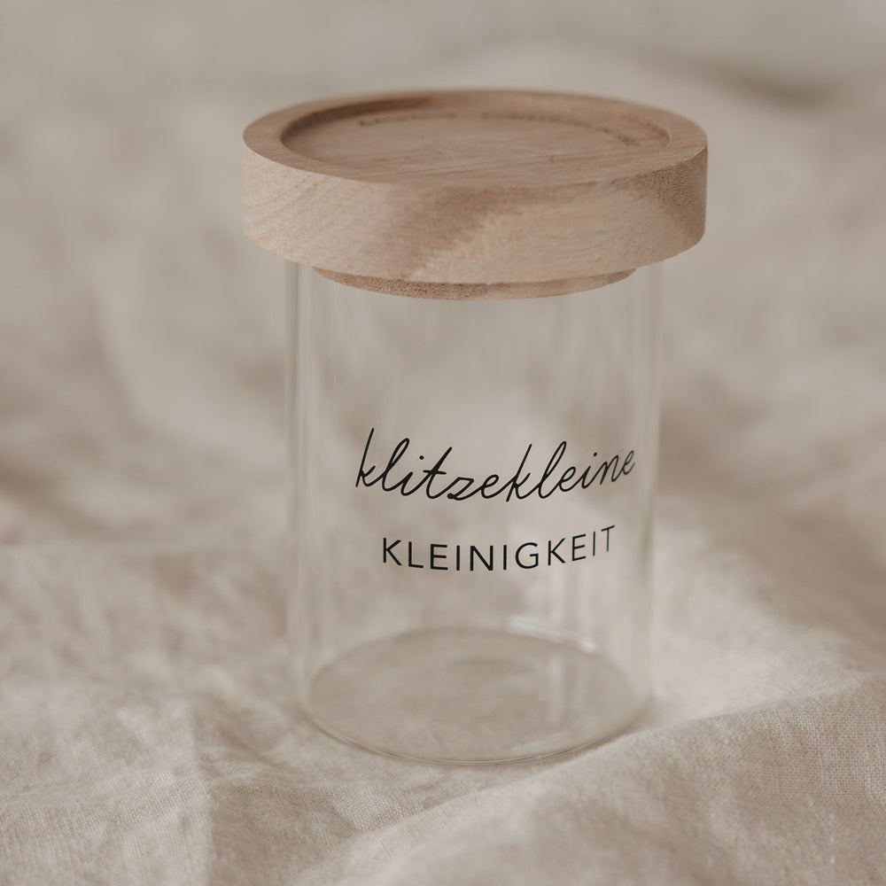 Minivorratsglas mit Holzdeckel und Schriftzug „klitzekleine Kleinigkeit“ auf hellem Hintergrund