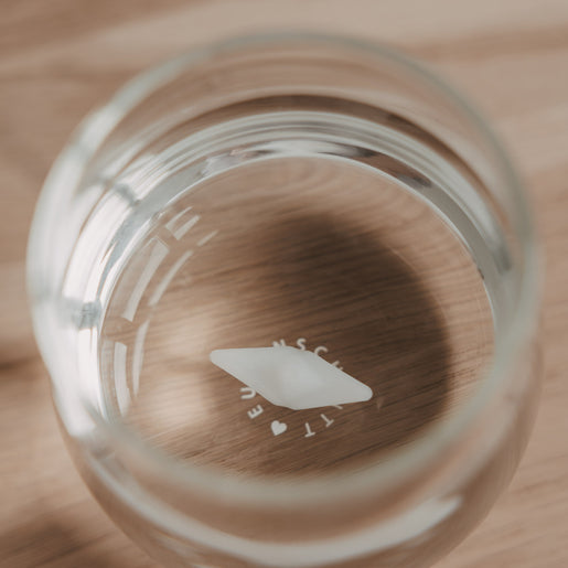 Draufsicht auf Glas mit Papierboot Detail im Boden, modernes Trinkglas Design