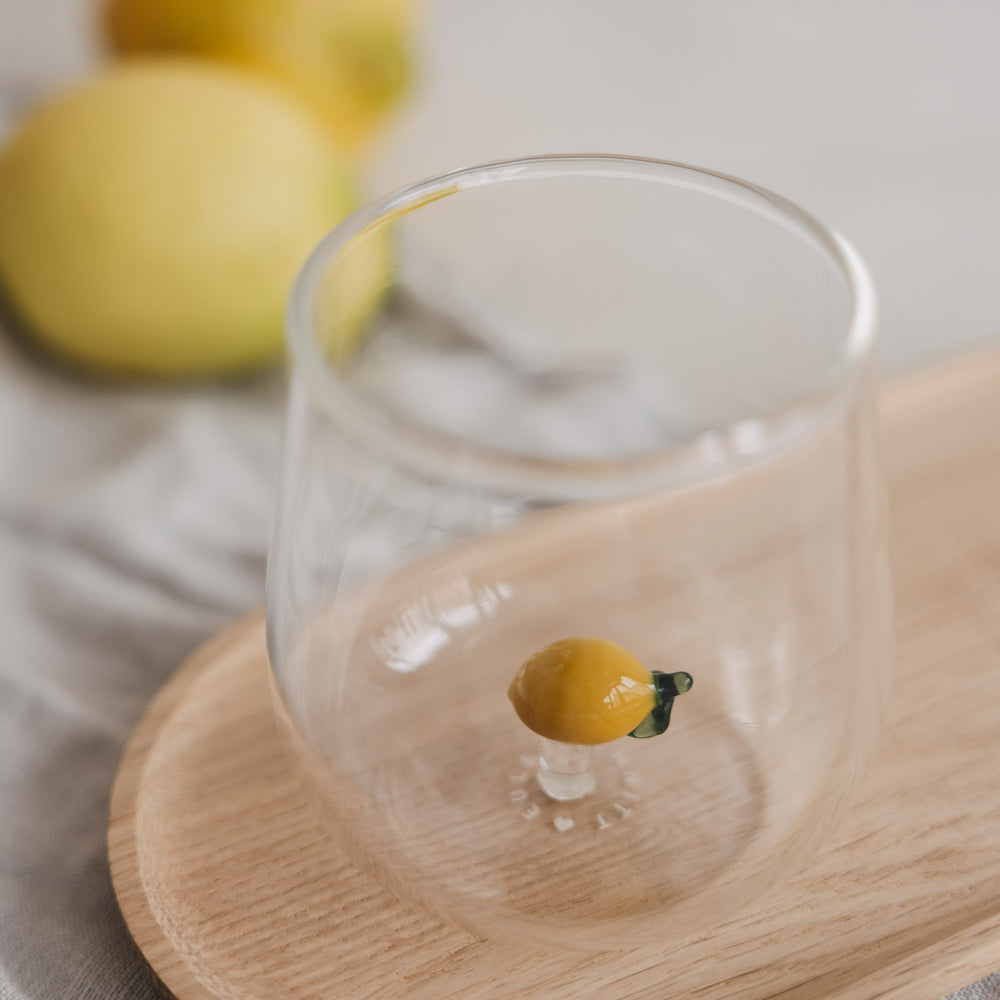 Minimalistisches Trinkglas mit Zitronen Design, klares Glas für Wasser auf Holztablett