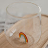 Detailaufnahme Glas mit buntem Regenbogen am Boden, modernes Trinkglas auf Holztablett
