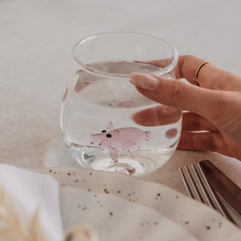 Trinkglas mit Schwein Motiv im Glasboden, in der Hand gehalten, gefüllt mit Wasser