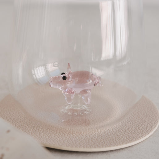 Transparentes Glas mit integrierter Schwein-Figur, dekoratives Doppelwandglas auf hellem Untergrund