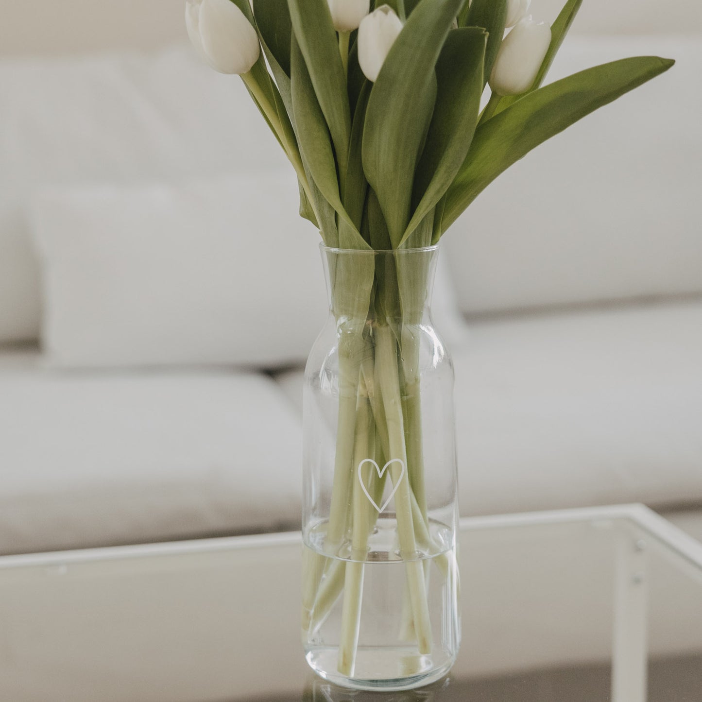 Glaskaraffe mit weißen Tulpen und Herzmotiv, stilvolle Wohnraumdekoration