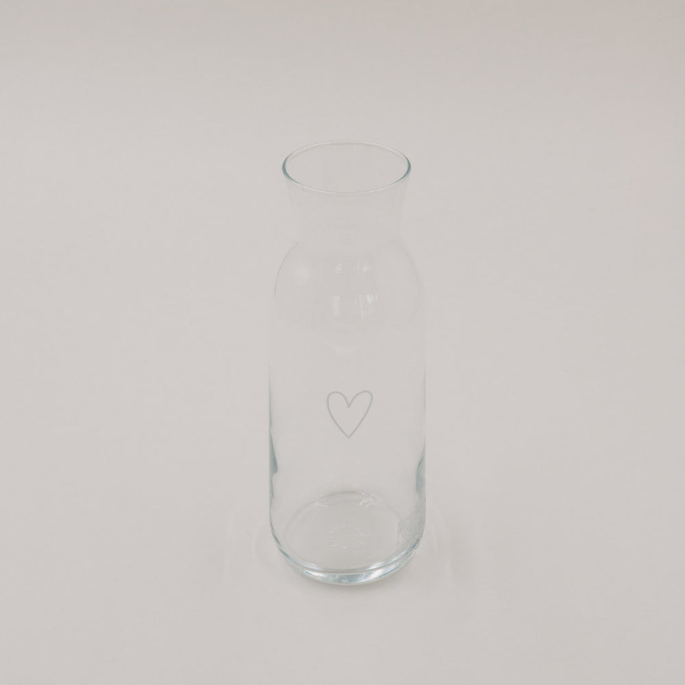 Schlichte Glaskaraffe mit Herzmotiv, modernes Design, freigestellt auf hellem Hintergrund