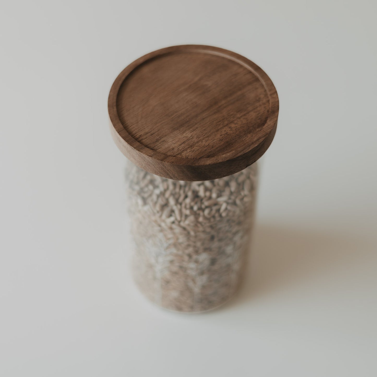 Detailansicht des runden dunklen Holzdeckels eines Glas-Vorratsbehälters mit Wildblumen-Motiv