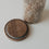 Abgenommener Holzdeckel mit schwarzem Dichtungsring neben einem Glas-Vorratsbehälter mit weißem Blumenmotiv