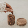 Offenes Mini Vorratsglas mit Sternen und Mandeln, daneben der abgenommene Holzdeckel