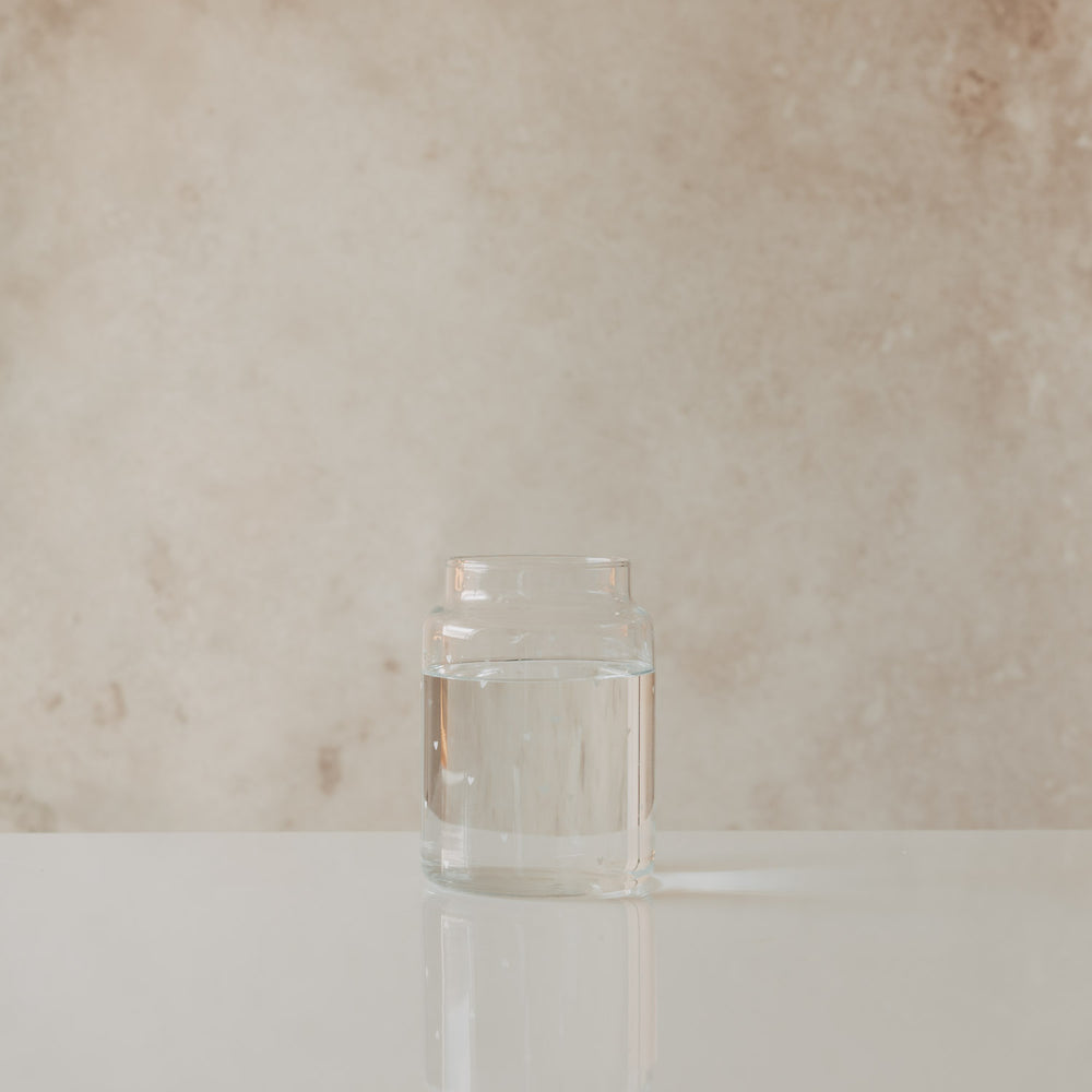 Schlichte Glasvase mit Wasserfüllung und zarten weißen Herzen