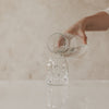 Glasvase mit schwarzem Herzprint, wird mit Wasser befüllt