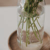 Detailaufnahme einer Glas Karaffe mit Blumenprint und eingesetzten Pflanzenstielen