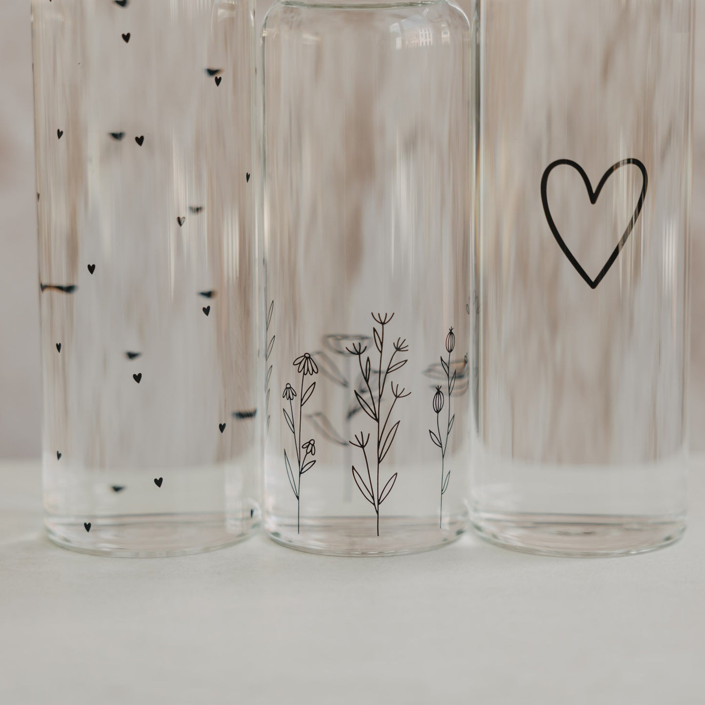 Glas Trinkflaschen mit Herz und Blumenwiese Design in Nahaufnahme, minimalistisch