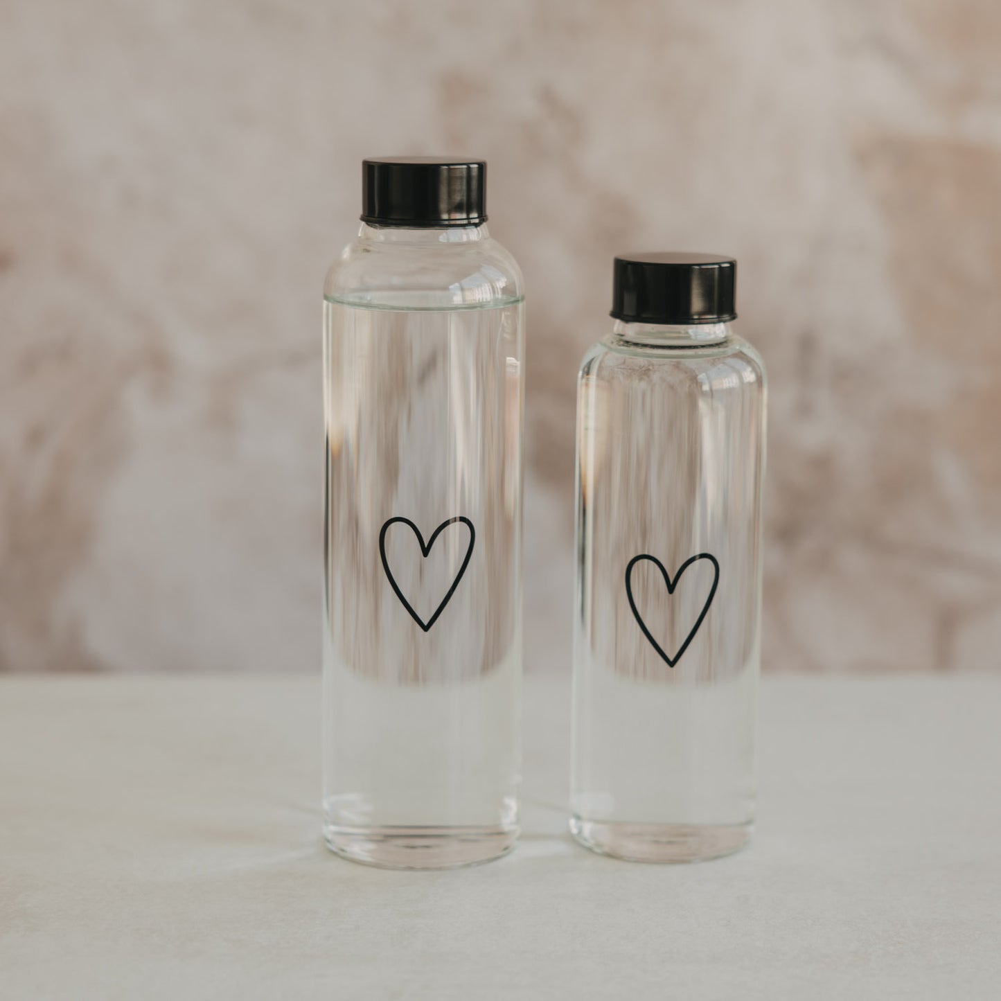 Zwei Glas Trinkflaschen Herz 750 ml und 500 ml im Vergleich, schlichtes Design mit schwarzem Deckel