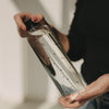 Trinkflasche aus Glas mit Herzmuster, schräg gehalten, modernes Design, Nahaufnahme in der Hand