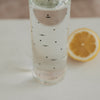 Glas Trinkflasche mit schwarzen Mini-Herzen 750 ml, gefüllt mit Wasser, Zitronenscheibe im Hintergrund