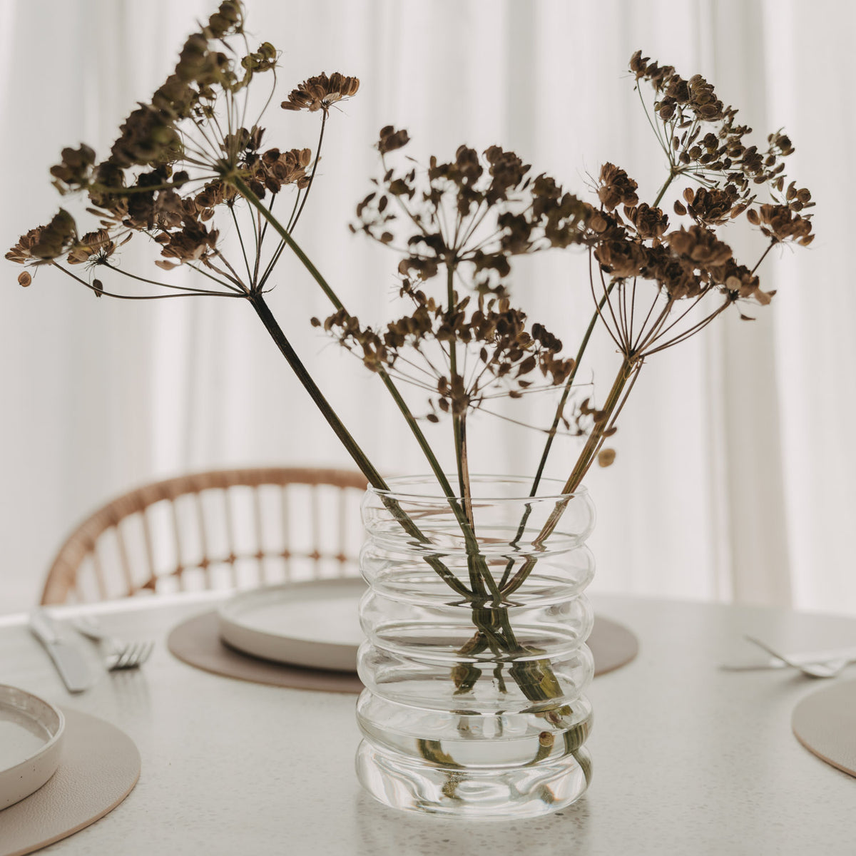 Bubble Vase aus transparentem Glas mit getrockneten Doldenblüten als Tischdekoration.