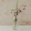 Glaskaraffe mit kleinen schwarzen Herzen als Vase mit rosa und violetten Blumen