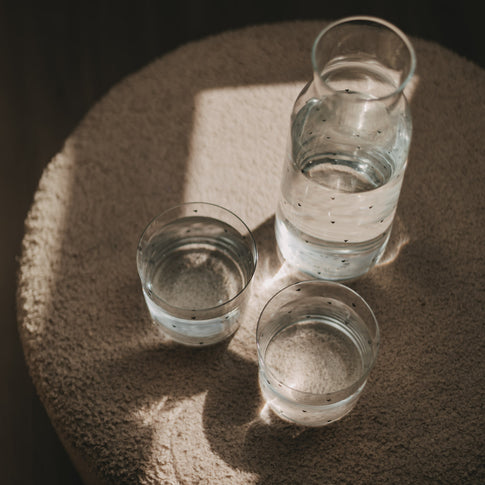 Glaskaraffe und zwei Wassergläser mit kleinen Herzen im warmen Sonnenlicht