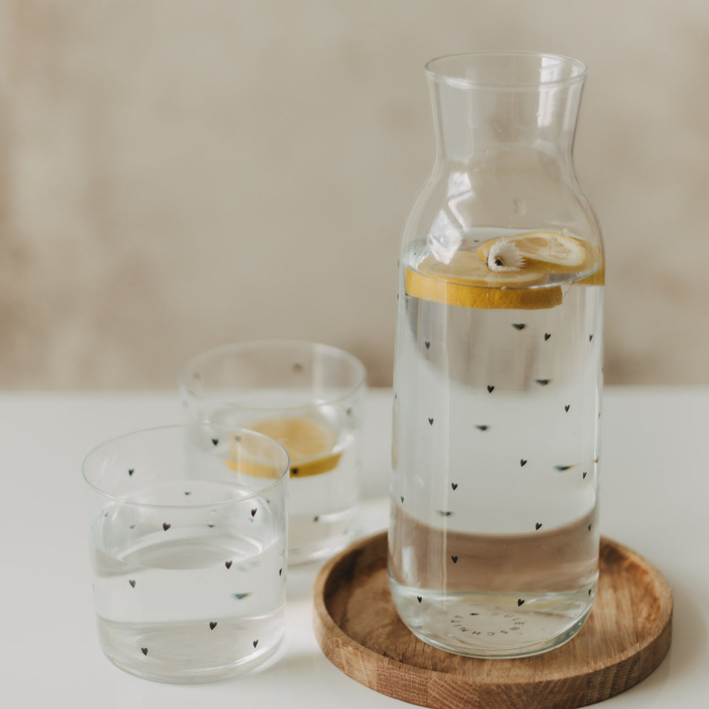Glaskaraffe und zwei Gläser mit Herzmuster, Wasser und Zitronenscheiben