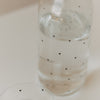 Detailaufnahme der mit Wasser gefüllten Glaskaraffe mit kleinen schwarzen Herzen