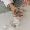 Hände gießen Wasser aus der Glaskaraffe mit Herzen in ein Trinkglas