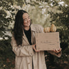 Frau hält Herbstbox mit Kürbissen im Freien, Geschenkidee für den Herbst mit Naturdeko und liebevoller Verpackung.