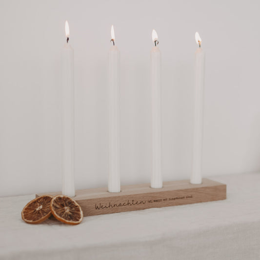 Adventskerzenbrett mit vier brennenden weißen Kerzen und Trockenorangen-Deko