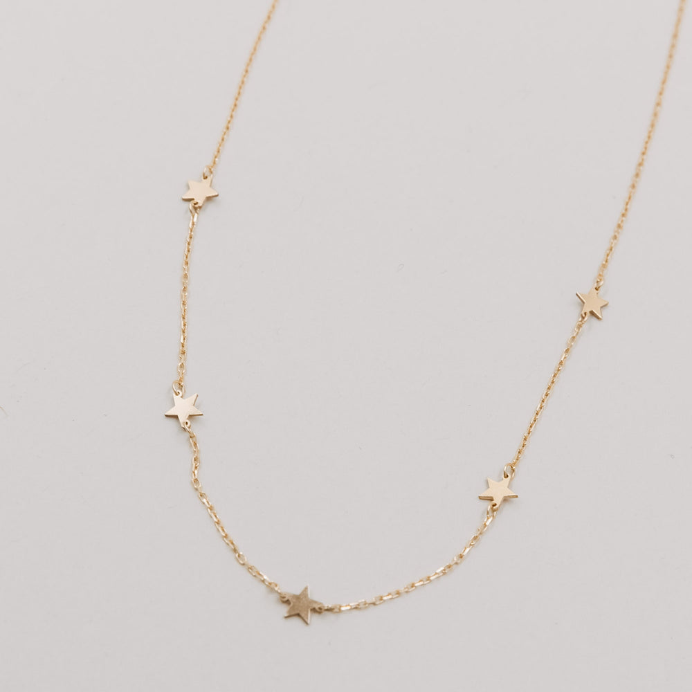 Produktansicht der goldenen Kette Jackie mit filigranen Sternenanhängern auf hellem Untergrund