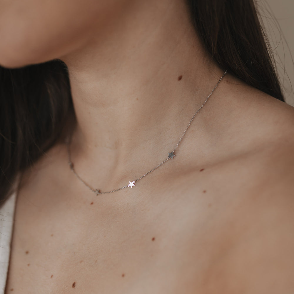Zarte silberne Kette mit kleinen Sternenanhängern getragen am Hals.