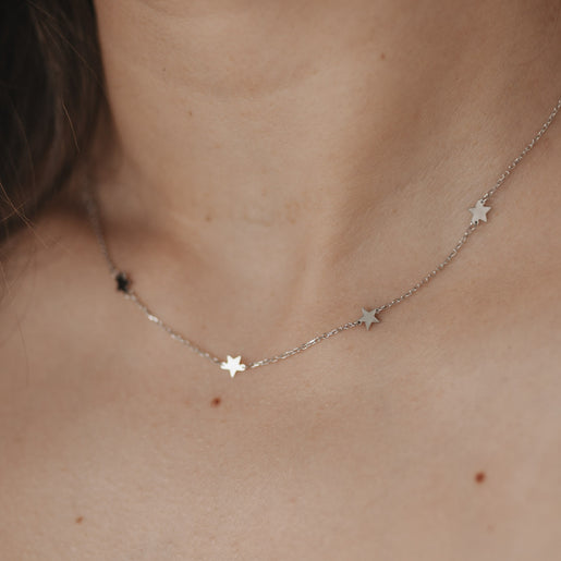 Zarte silberne Kette mit kleinen Sternenanhängern getragen am Hals.