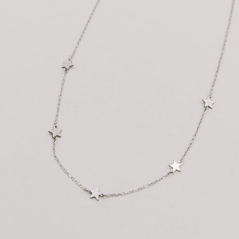 Silberne Kette mit kleinen, glänzenden Sternanhängern auf weißem Hintergrund.